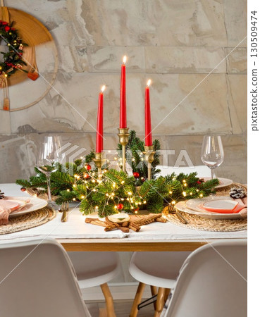 Festive Christmas Table Setting with Red Candles and Garland Decoration Indoors 130509474