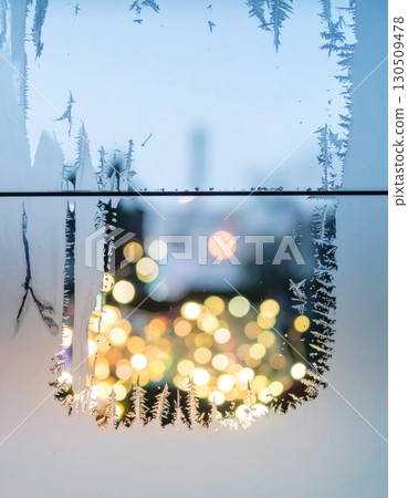 Frosted Window with Ice Crystals and Bokeh Lights Creating a Festive Winter Scene 130509478
