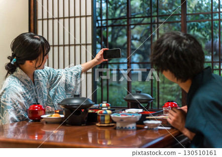 Couple in yukata taking selfies with smartphone at hot spring inn, inn, dining in room, dinner 130510161