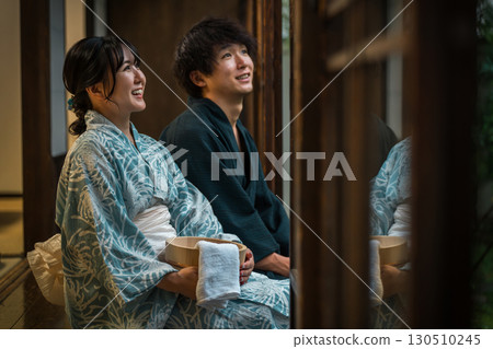 Couples in yukata enjoying the cool evening breeze on the veranda of a hot spring inn, temple lodging, or traditional Japanese house 130510245