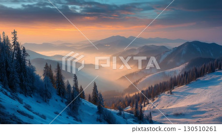 Beautiful golden light shines across the vast snowy mountains with mist filling the valleys below 130510261