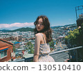 A young Korean woman looks back from a city balcony wearing a floral dress 130510410