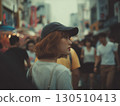 A young Korean woman wearing a cap looks to the side on a busy street 130510413