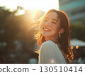A lovely Korean woman smiles widely turning her face into the golden evening sun 130510414