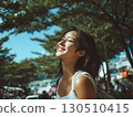 A Korean woman smiles eyes closed feeling the bright sun on her face outdoors 130510415