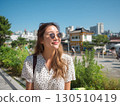 A happy Korean woman with sunglasses gazes up smiling in the bright sunshine 130510419