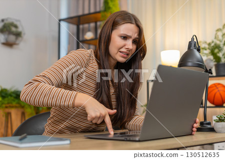 Young woman waves hand in frustration as laptop freezes with virus glitch error then exhales to calm Young woman waves hand in frustration as laptop freezes with virus glitch error then exhales to calm 130512635