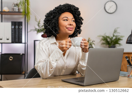 African American businesswoman drinks coffee thinking near window resting from work for inspiration African American businesswoman drinks coffee thinking near window resting from work for inspiration 130512662