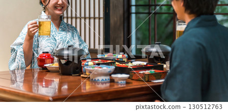 一對穿著浴衣的夫婦一邊享用宴會,一邊喝著生啤 一對穿著浴衣的夫婦一邊享用宴會,一邊喝著生啤 130512763