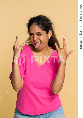 Indian woman making energetic rock-n-roll hand gesture, happily dancing like energetic rock star 130512809