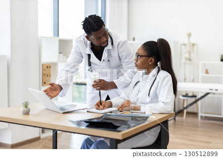Two adult medical professionals, male and female colleagues, collaborating in modern healthcare setting 130512899