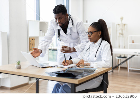 Two adult medical professionals, male and female colleagues, collaborating in modern healthcare setting 130512900