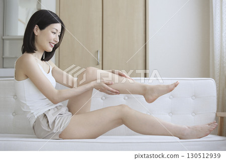 An adult woman doing foot care in the living room 130512939