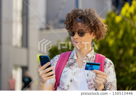 Tourist man using credit bank card smartphone while transferring money, purchases online shopping Tourist man using credit bank card smartphone while transferring money, purchases online shopping 130513446