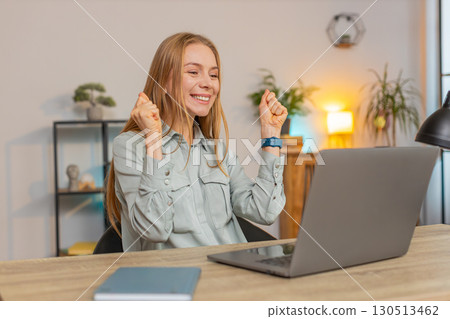 Excited Caucasian woman working on laptop shocked by sudden victory sitting at home office desk Excited Caucasian woman working on laptop shocked by sudden victory sitting at home office desk 130513462