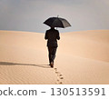a man in a dark suit and an open umbrella walks under the desert sun 130513591