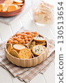 Various salty snacks in a round bowl on white table. 130513654