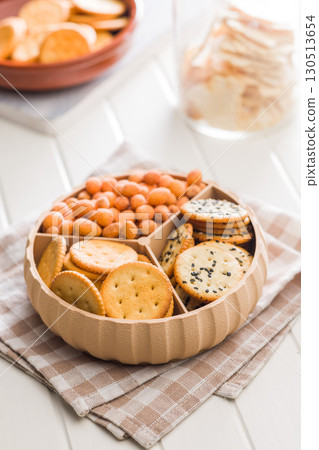 Various salty snacks in a round bowl on white table. Various salty snacks in a round bowl on white table. 130513654