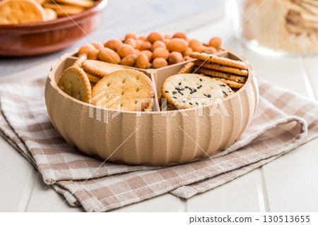 Various salty snacks in a round bowl on white table. 130513655