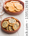 Crispy round salted crackers in bowl on white table. 130513658