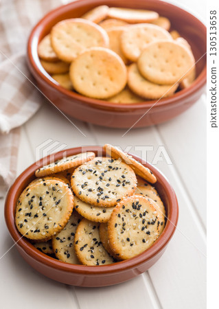 Crispy round salted crackers in bowl on white table. 130513658