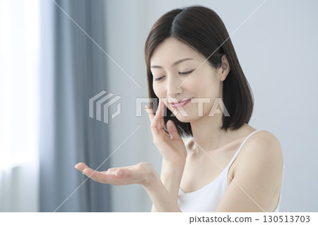 一位日本女性在客廳往手掌上塗抹護膚霜 一位日本女性在客廳往手掌上塗抹護膚霜 130513703