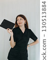 skilled aesthetician woman professional wearing black medical suit holding a ckipboard 130513884