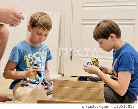 boys helping his father assemble a new piece of furniture with a screwdriver boys helping his father assemble a new piece of furniture with a screwdriver 130513892