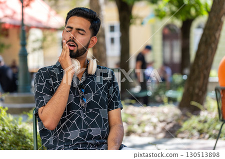 Frustrated sick ill Indian man touching cheek suffer from painful toothache sensitive teeth cavities 130513898