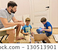 boys helping his father assemble a new piece of furniture with a screwdriver 130513901