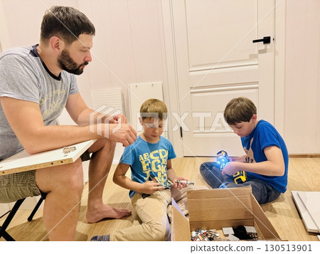 boys helping his father assemble a new piece of furniture with a screwdriver 130513901