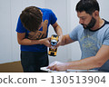 teen age boy helping his father assemble a new piece of furniture with a screwdriver 130513904