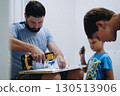 man assembling a new furniture with a screwdriver. children helping him 130513906