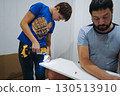 teen age boy helping his father assemble a new piece of furniture with a screwdriver 130513910