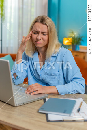 Tired ill businesswoman suffering from headache problem tension migraine stress at home office desk 130513963
