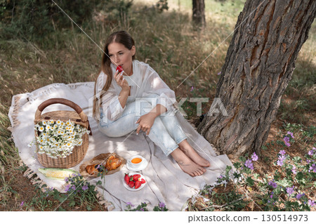 Picnic Woman Strawberries: Woman enjoys summer picnic with food under tree to relax in nature. Picnic Woman Strawberries: Woman enjoys summer picnic with food under tree to relax in nature. 130514973