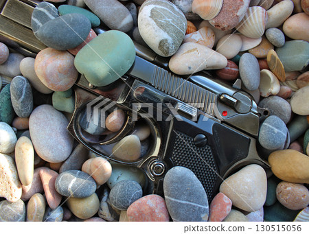 Discarded Automatic Pistol Gun Half Buried In Sea Stones Discarded Automatic Pistol Gun Half Buried In Sea Stones 130515056