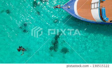 Aerial view of scuba divers floating on the surface over turquoise crystal clear water near the boat 130515122