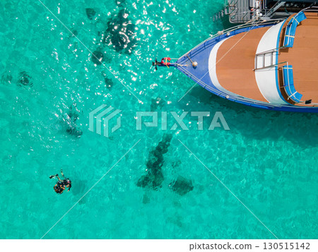 Aerial view of scuba divers floating on the surface over turquoise crystal clear water near the boat Aerial view of scuba divers floating on the surface over turquoise crystal clear water near the boat 130515142