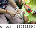 A skilled dental professional demonstrates oral care methods using a model while engaging with a young patient in a comfortable clinic environment. 130515398