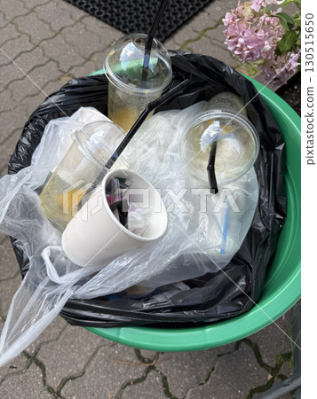 Overflowing trash can with various plastic and paper waste outdoors on a paved surface Overflowing trash can with various plastic and paper waste outdoors on a paved surface 130515650