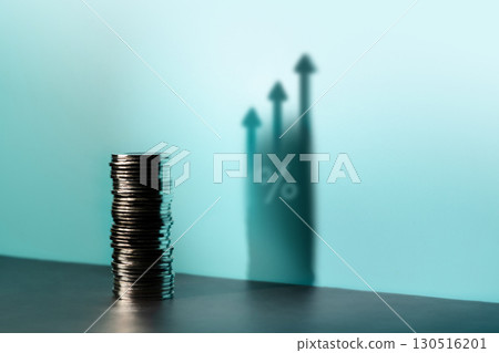 Coins stacked cast a tall upward arrow shadow and Percentage, reflecting financial growth, investment optimism, and a hopeful economic outlook 130516201