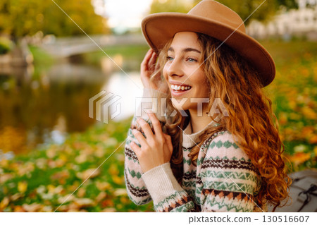 Portrait of a stylish smiling woman walking in park. street style in hat. Concept of nature, relax. Portrait of a stylish smiling woman walking in park. street style in hat. Concept of nature, relax. 130516607