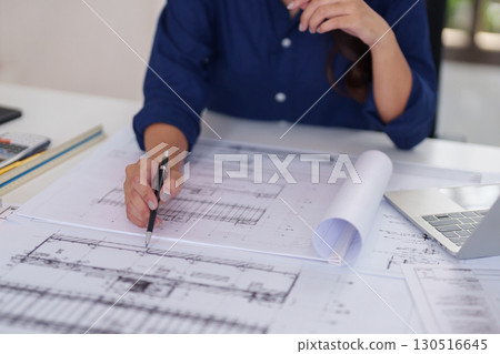 Asian adult architect hands expertly drafting detailed architectural blueprints at office desk designing innovative building solutions engineering plans 130516645