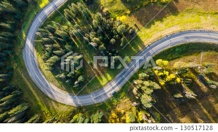 Aerial drone footage of S curve road winding through green pine and aspen forest 130517128