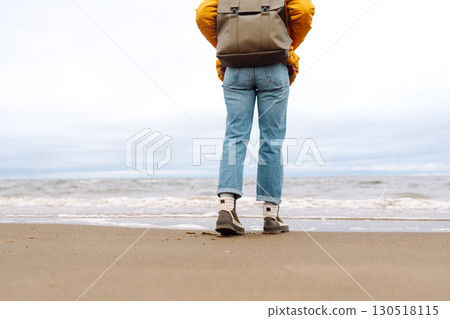 Close-up of woman's legs in boots. Tourist walk along beach near sea. Adventure, vacation concept. Close-up of woman's legs in boots. Tourist walk along beach near sea. Adventure, vacation concept. 130518115