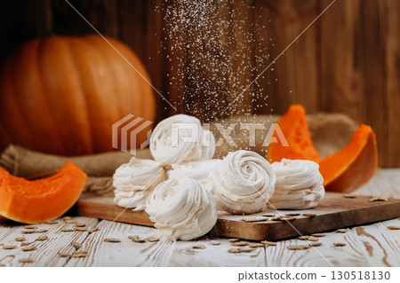 Pumpkin marshmallow sweets with powdered sugar falling, rustic autumn wooden background Pumpkin marshmallow sweets with powdered sugar falling, rustic autumn wooden background 130518130