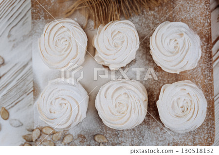 Pumpkin marshmallow meringues on a rustic wooden table, top view with powdered sugar Pumpkin marshmallow meringues on a rustic wooden table, top view with powdered sugar 130518132