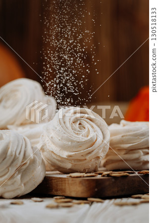 Pumpkin marshmallow sweets with powdered sugar falling, rustic autumn wooden background 130518133