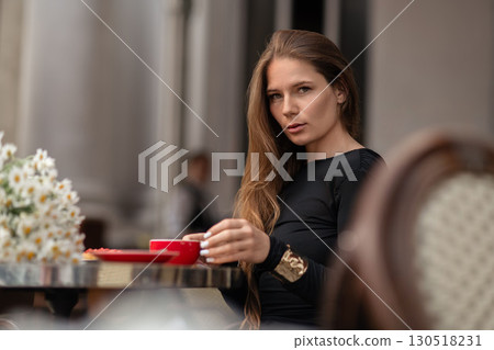 Woman Coffee Terrace: Young adult drinks coffee at outdoor cafe table during daytime, relaxing moment. Woman Coffee Terrace: Young adult drinks coffee at outdoor cafe table during daytime, relaxing moment. 130518231